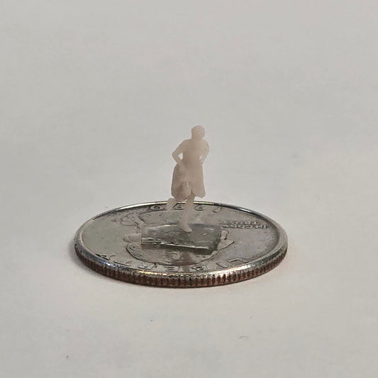 Unpainted N scale woman figure standing with hands on hips, wearing a dress and positioned on a U.S. quarter for scale reference.