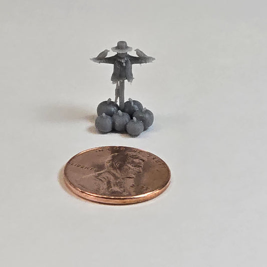 “Miniature Monday scarecrow with pumpkins — rear view next to a penny for scale”