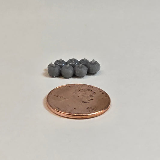 “Eight sculptural grey miniature pumpkins in two rows with a shiny penny for scale, displayed on a neutral background.”