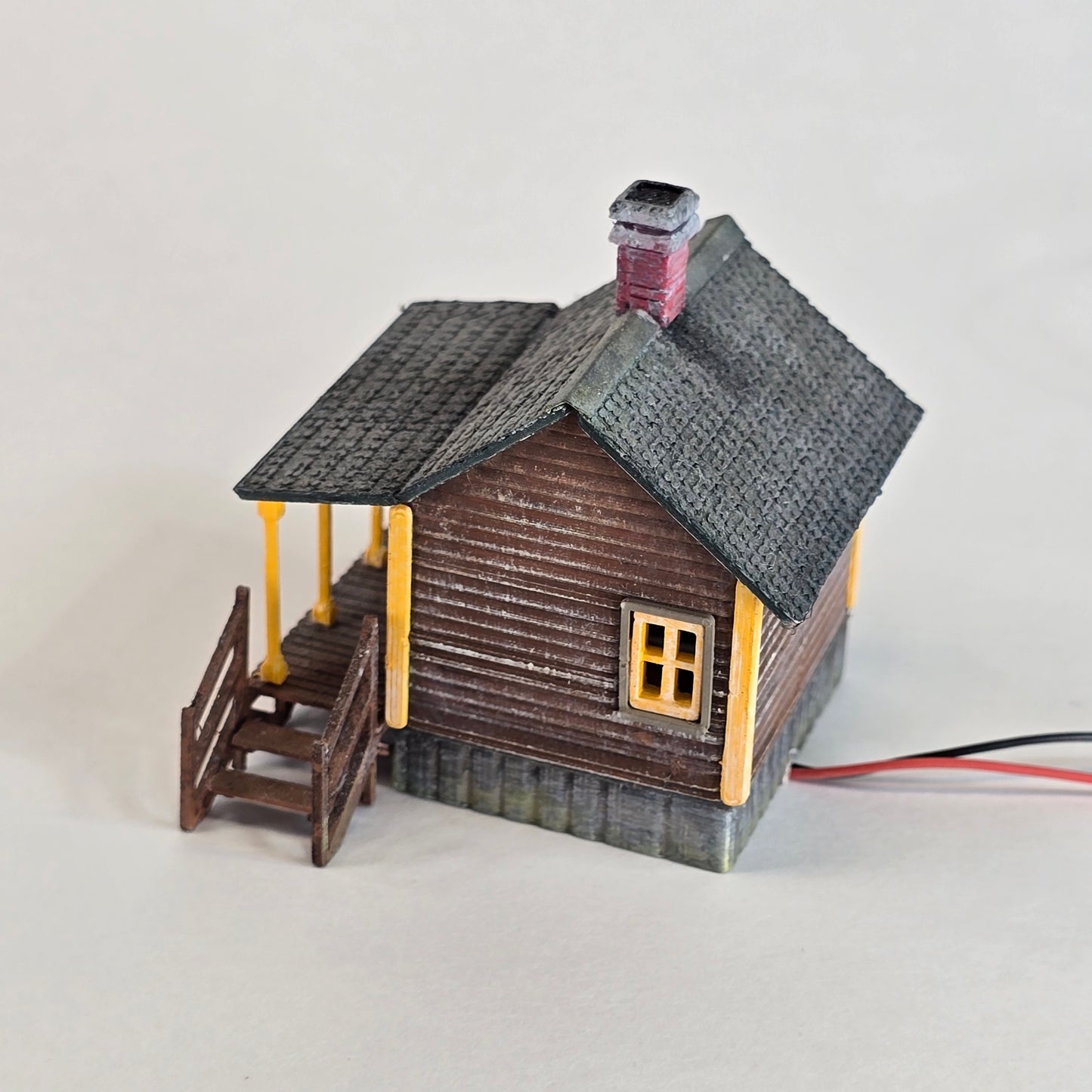 Small model of a house with textured walls and a gray roof on a white background